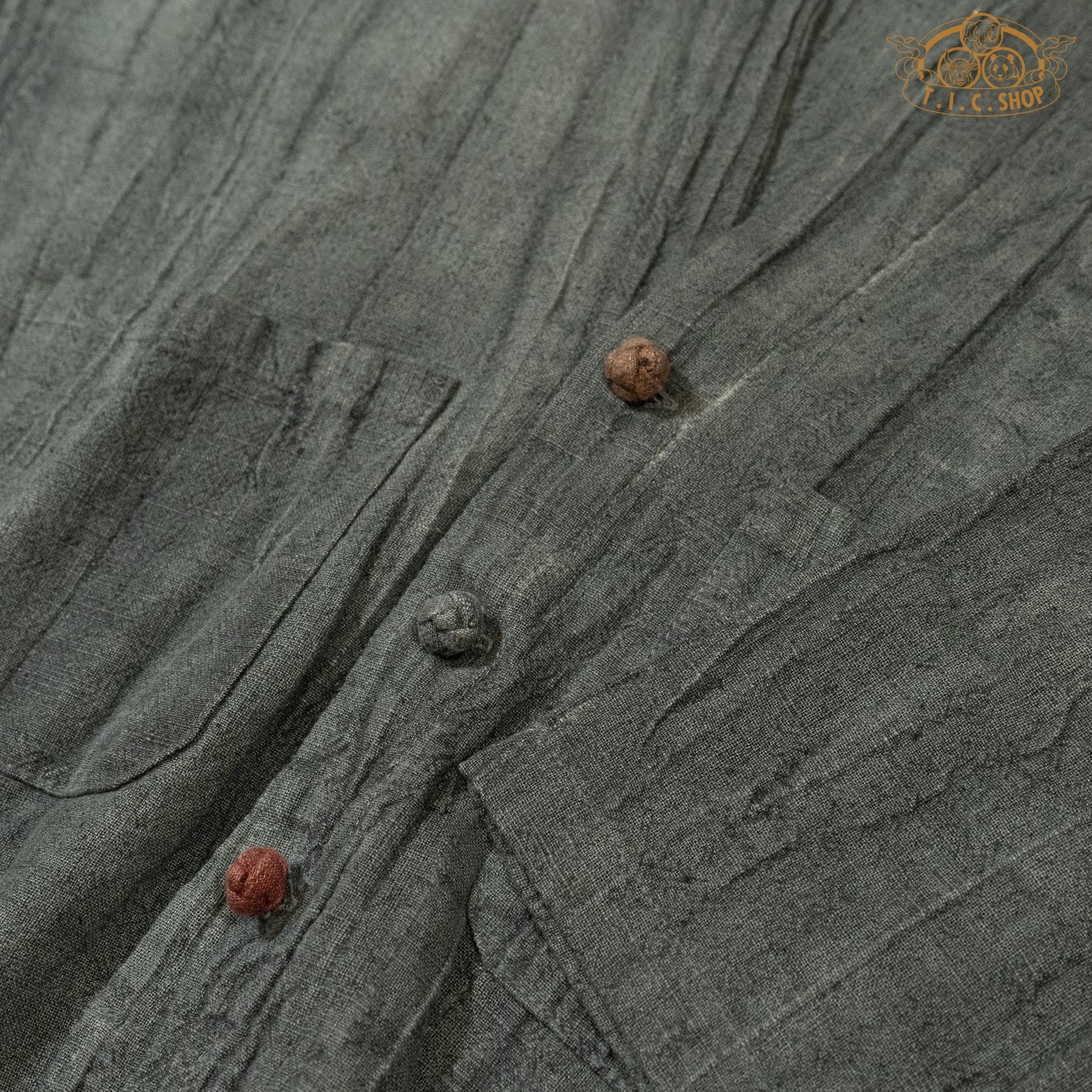 Detail shot of the multi-colored handmade buttons against the textured forest green linen fabric.