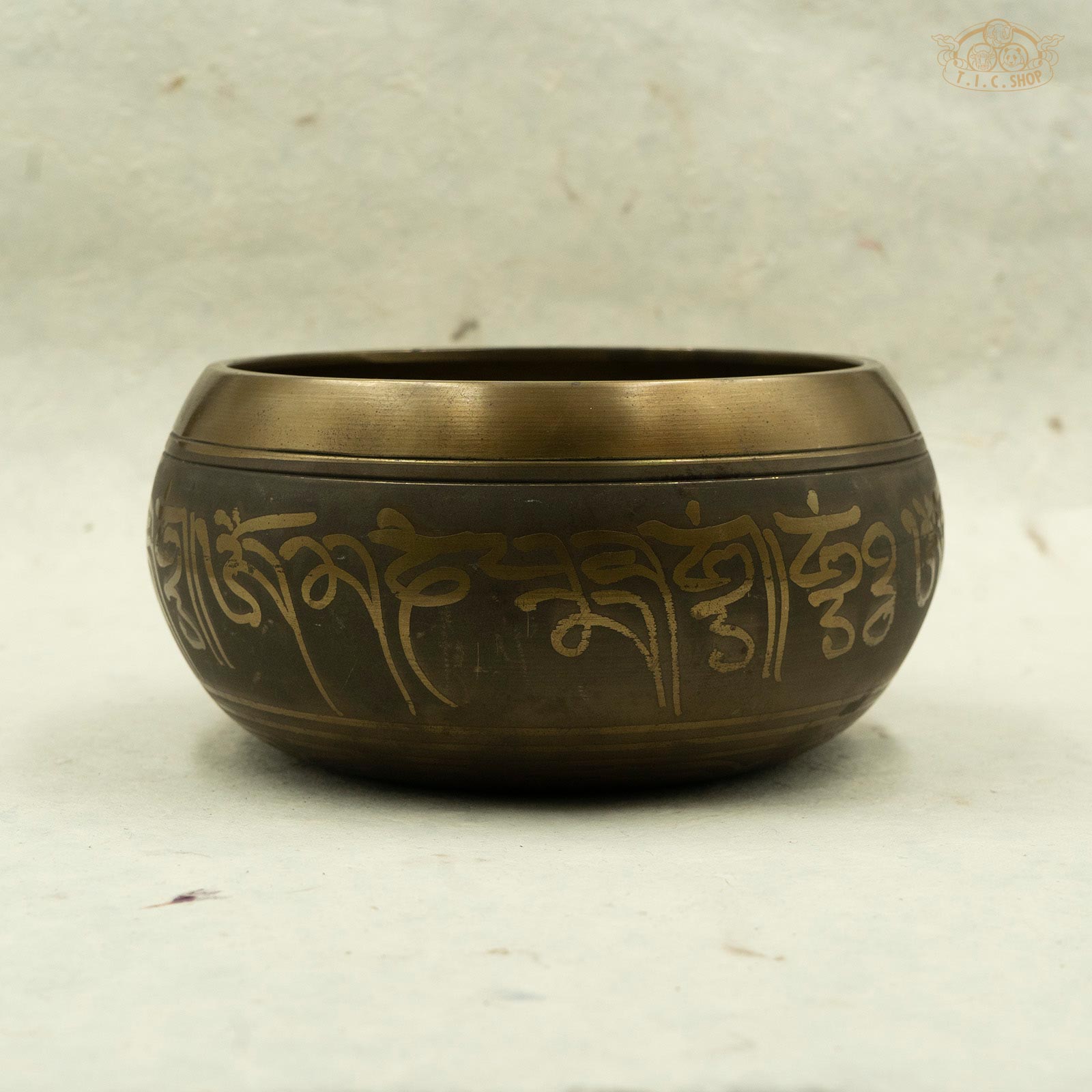 Side view of Tibetan brass singing bowl with an image of five buddhas seated around the rim, handcrafted in Nepal for meditation