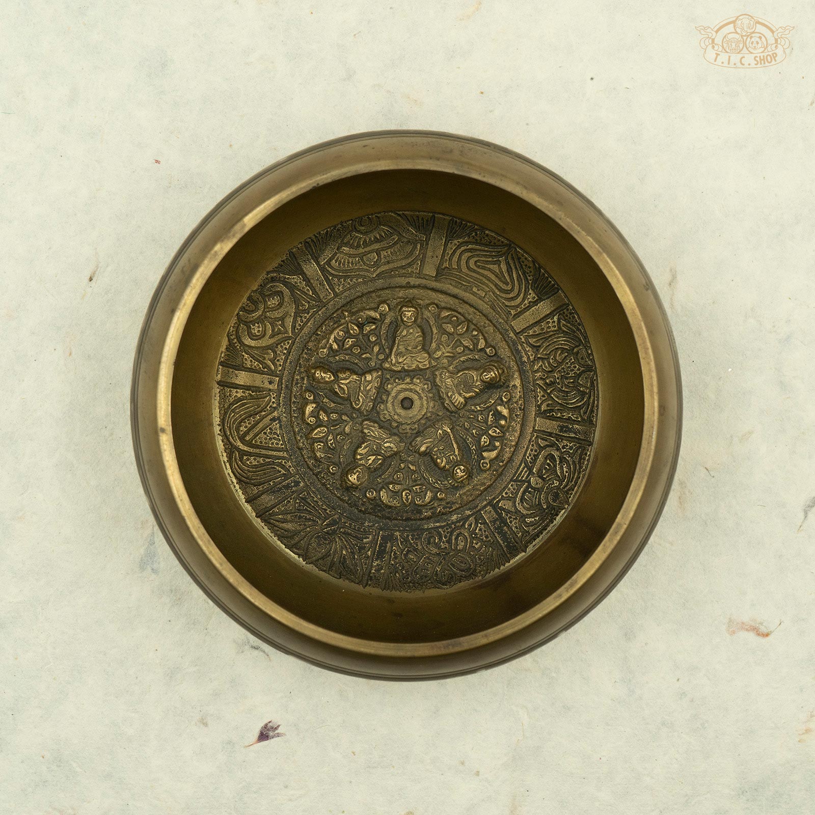 Top view of Tibetan brass singing bowl with an image of five buddhas seated around the rim, handcrafted in Nepal for meditation