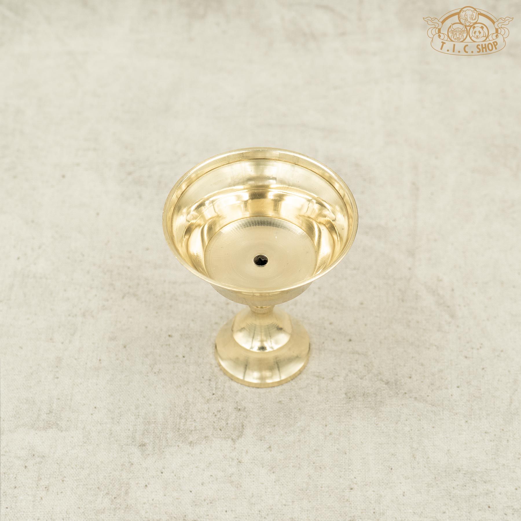 Top view of small Tibetan brass butter lamp showing round bowl and polished surface.