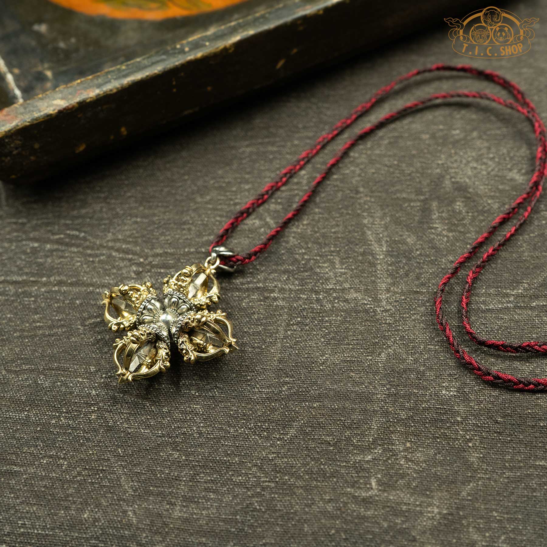 Angled side view of double vajra pendant showing sculpted details and depth