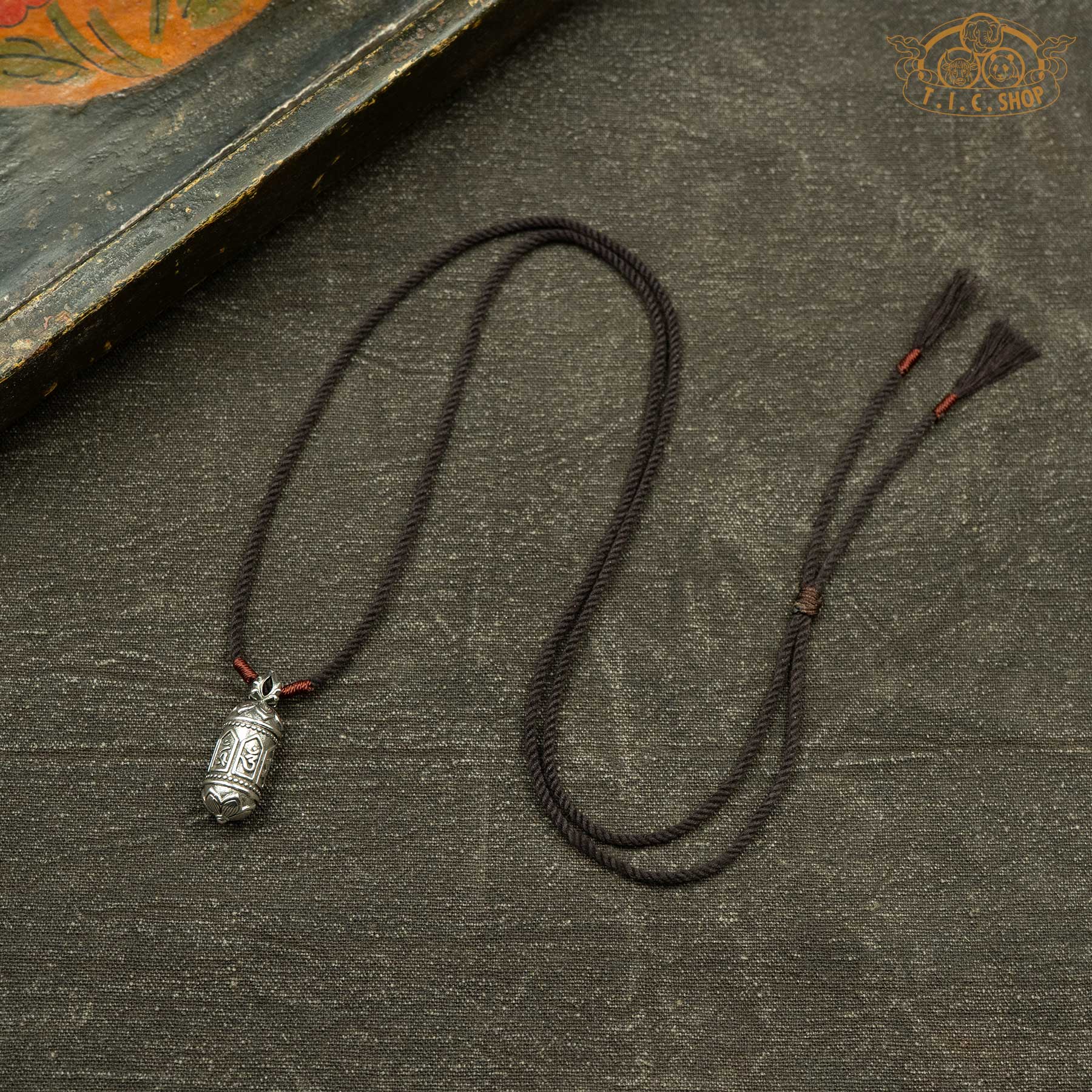 Gau amulet box pendant displayed with hand-woven brown rope necklace