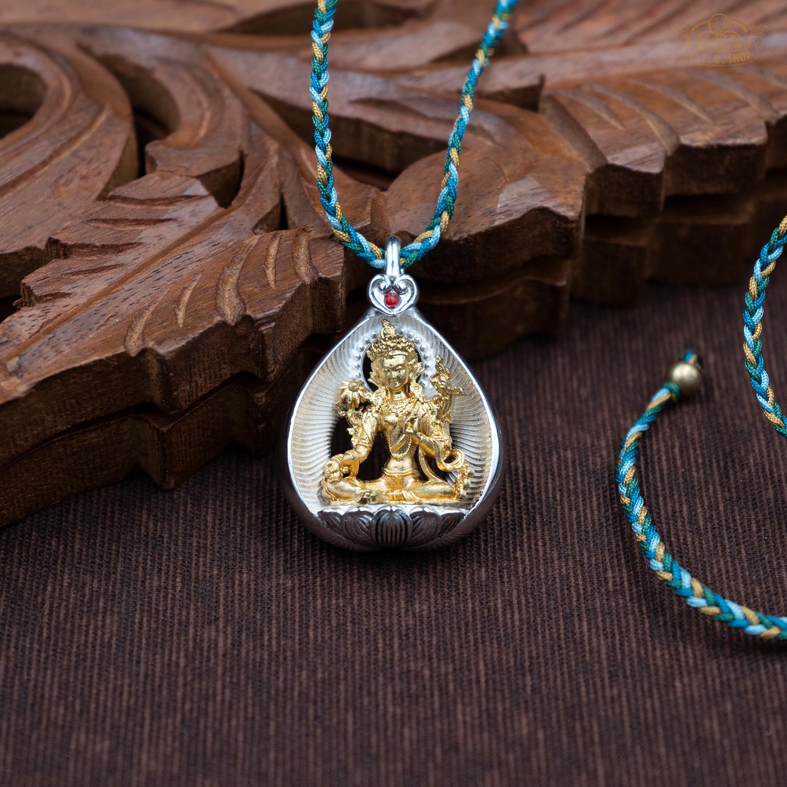 Amulet pendant featuring a brass Green Tara figure seated on a lotus, front view with finely carved details