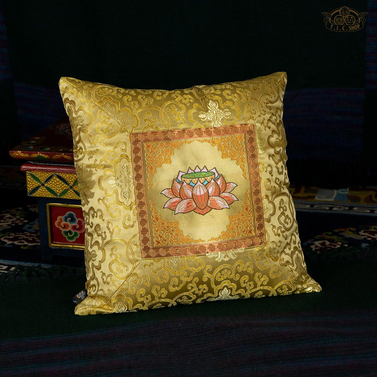 A cushion cover with traditional Tibetan style embroidery in gold color featuring a lotus pattern.