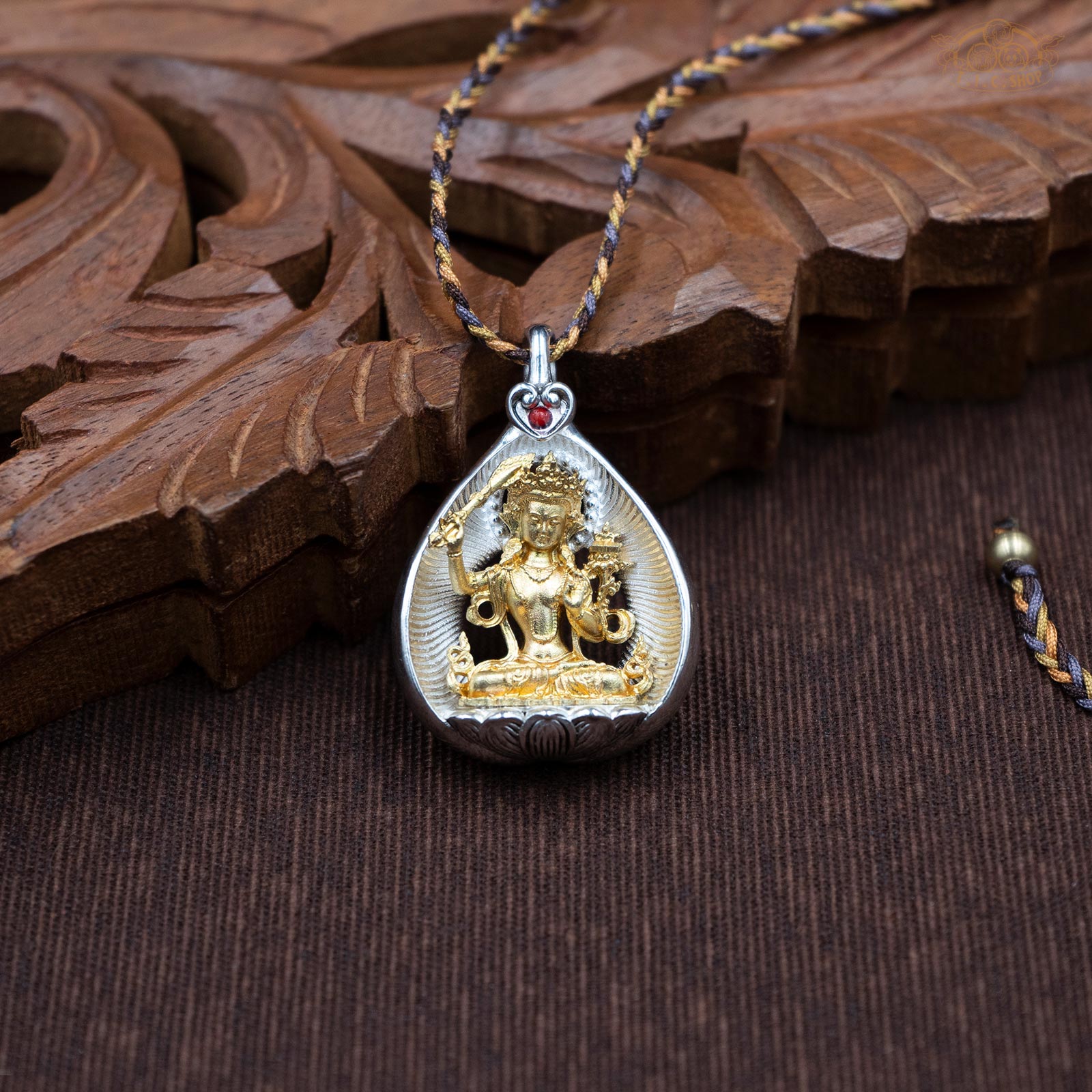 Amulet pendant featuring a brass Manjushri figure seated on a lotus, front view with finely carved details