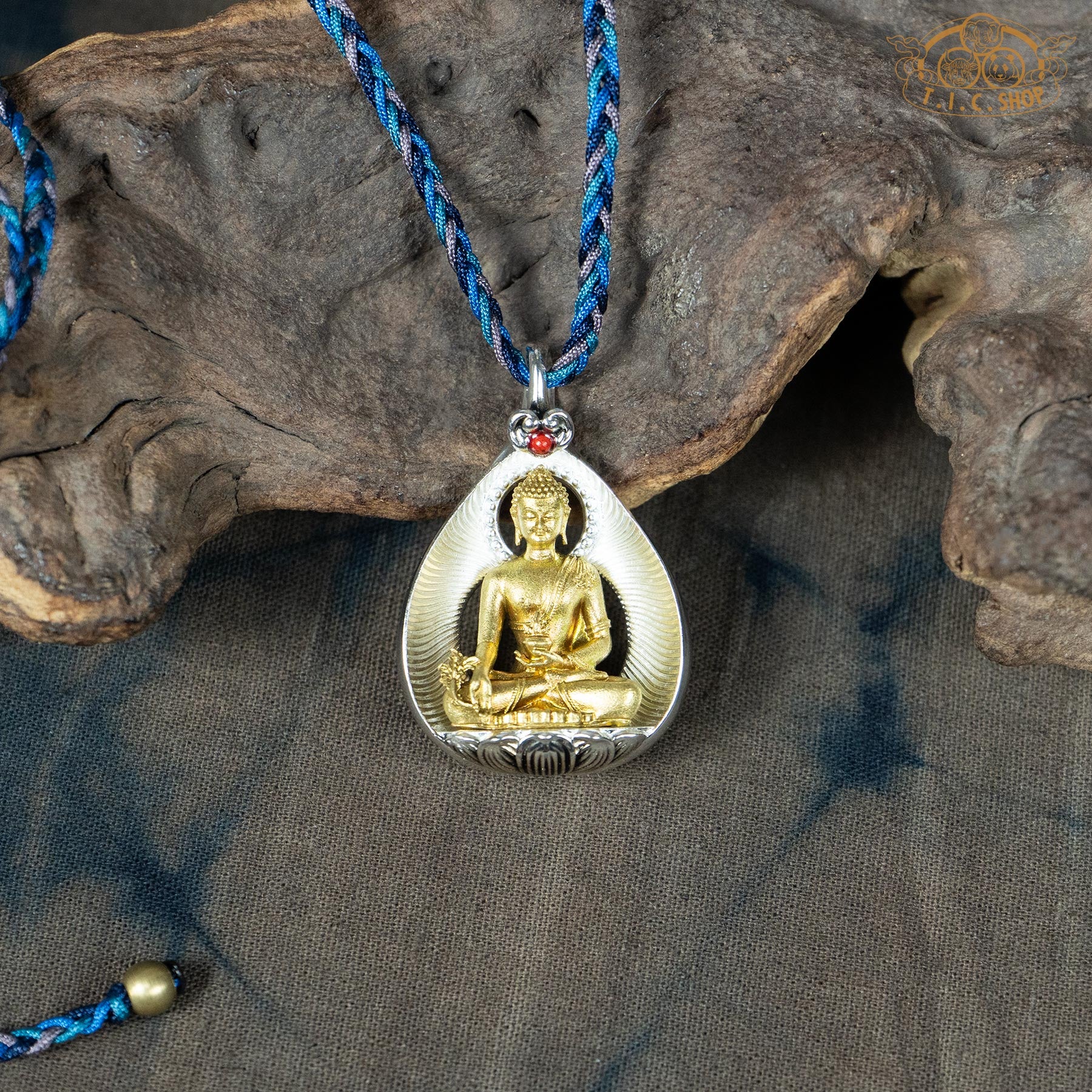 Amulet pendant featuring a brass Medicine Buddha figure seated on a lotus, front view with finely carved details