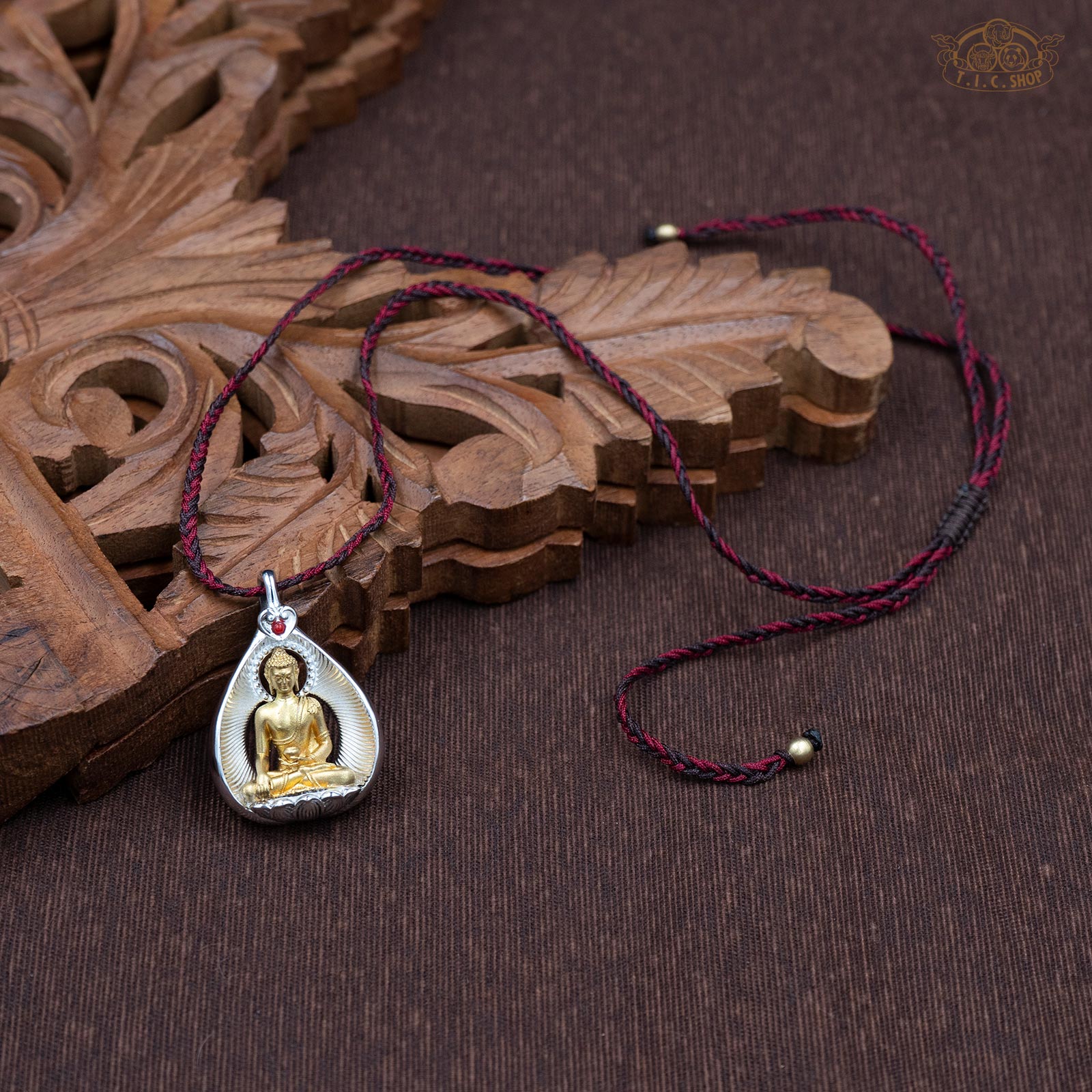 Sculpted Shakyamuni Buddha amulet pendant displayed with hand-woven red and brown rope necklace
