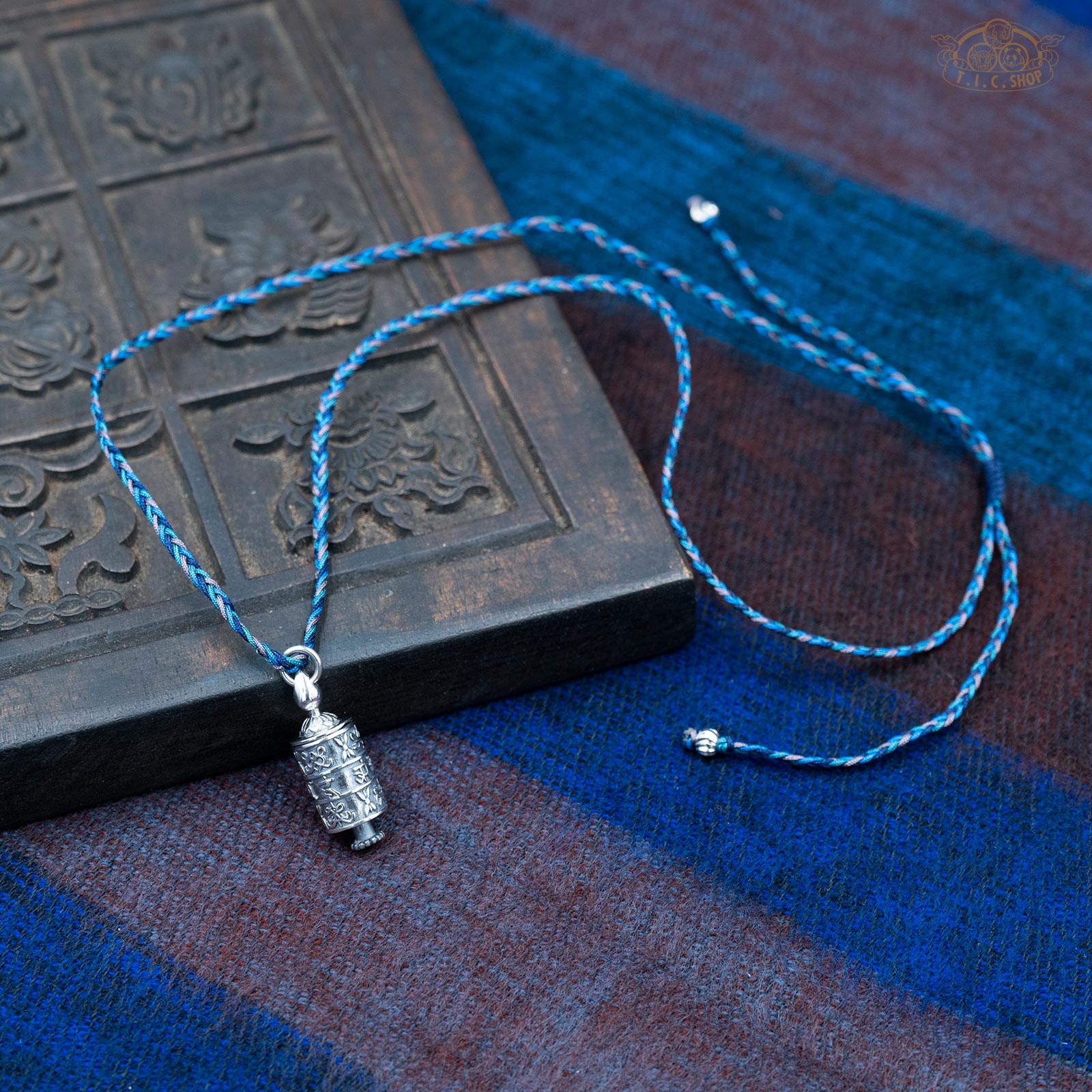 Silver Gau amulet box pendant displayed with hand-woven blue tone rope necklace