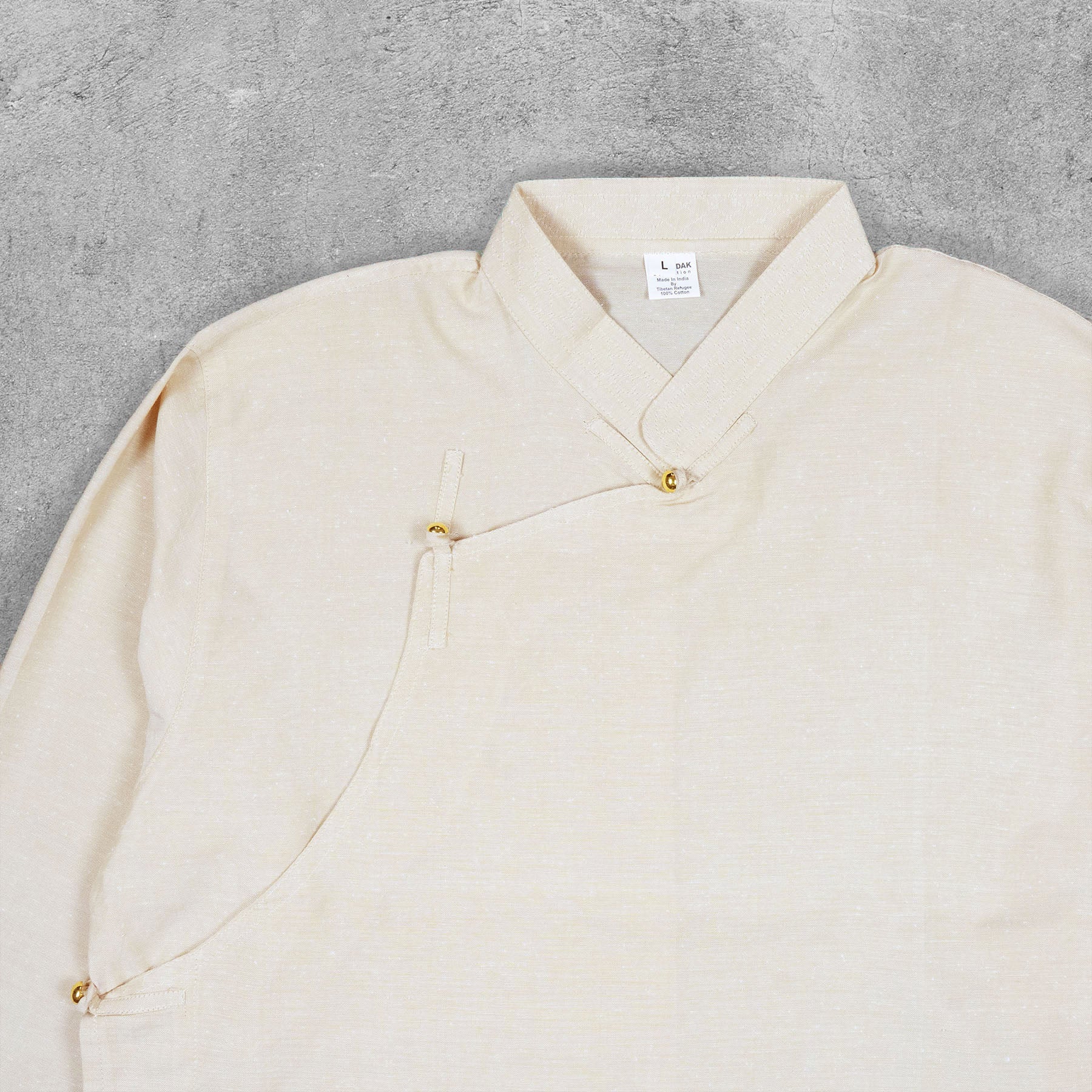 Close-up detail of the cotton fabric texture and stitching of the Tibetan-inspired shirt.