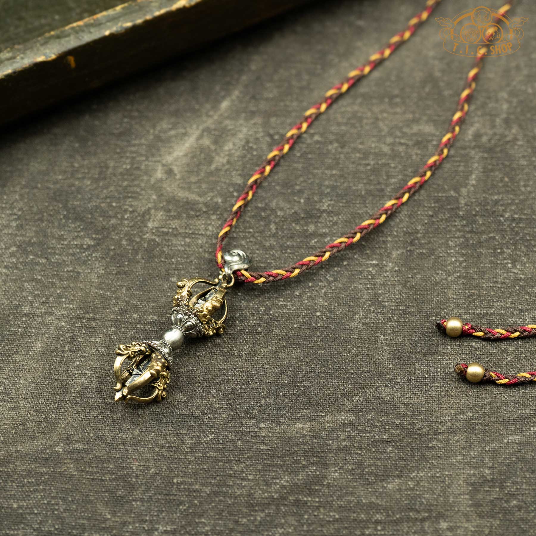 Angled side view of vajra pendant showing sculpted details and depth