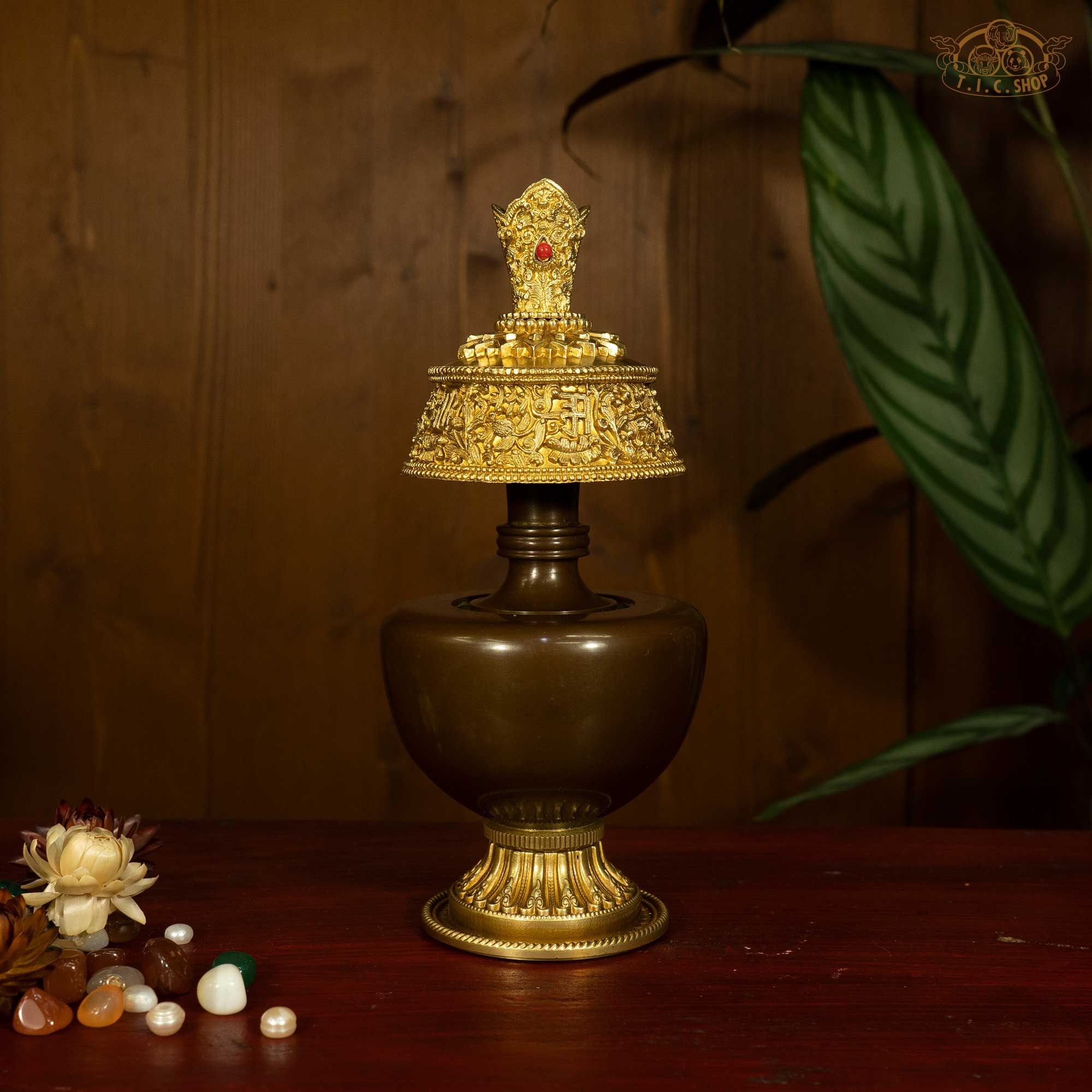 Front view of Tibetan brass Bumpa ritual vase with ornate crown top and red stone detail