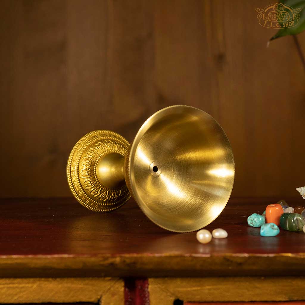 Side view of Tibetan brass butter lamp, showing detailed decorative motifs and traditional design.