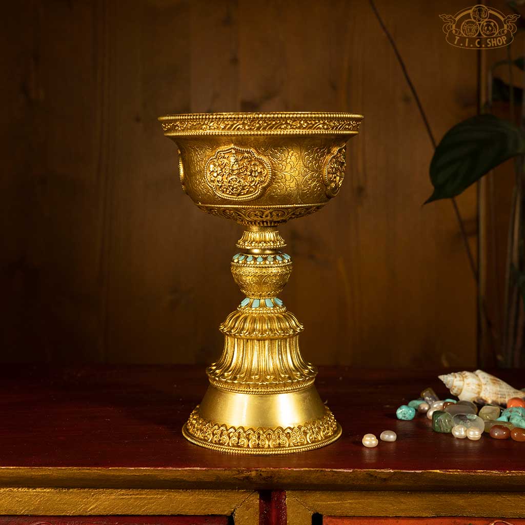 Front view of Tibetan brass butter lamp engraved with Eight Auspicious Symbols, lotus, and cloud motifs.