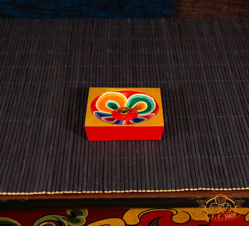 Side view of round wooden incense holder showing traditional Tibetan colors and craftsmanship.