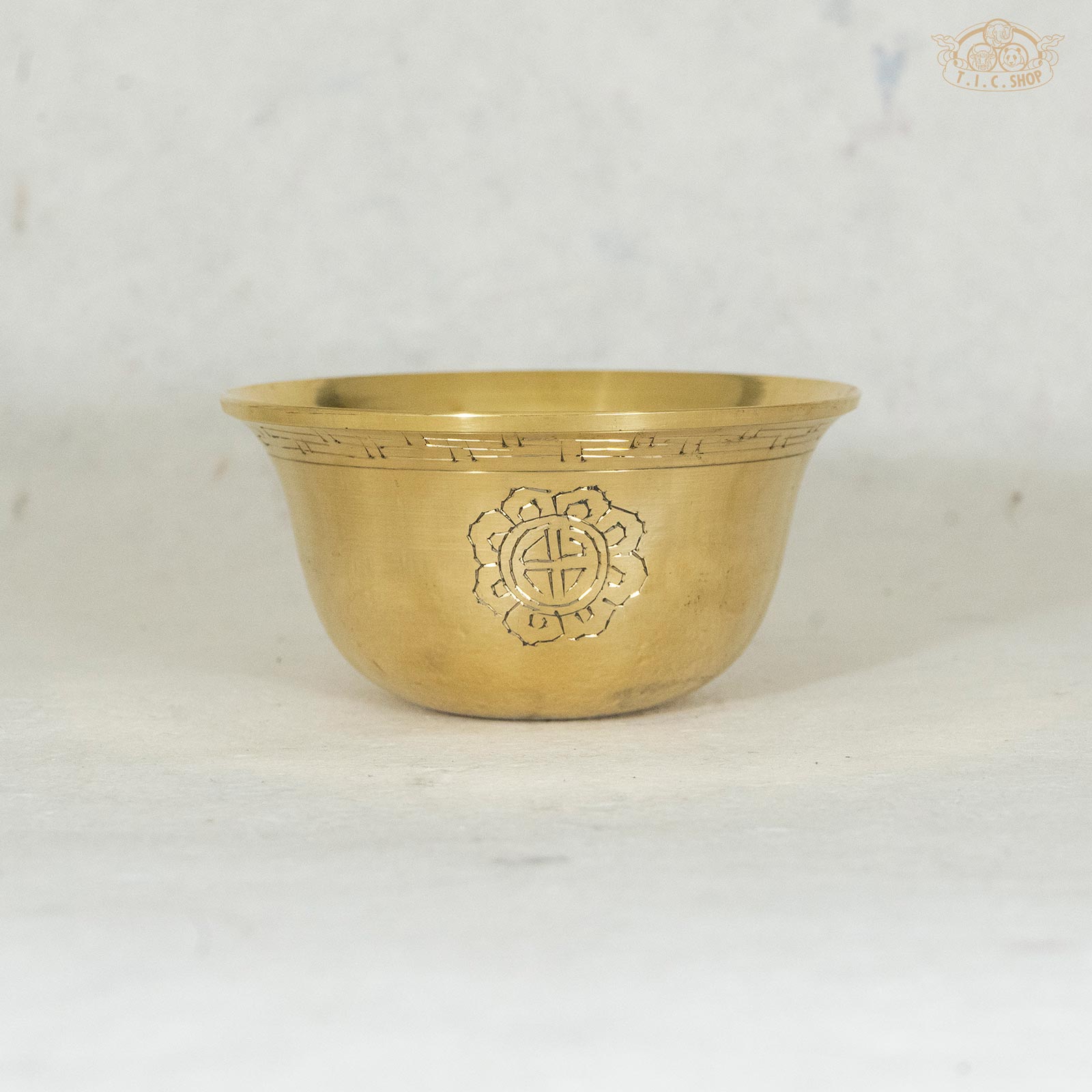 10cm Brass offering bowl with ornamental designs, displayed against a textured background.