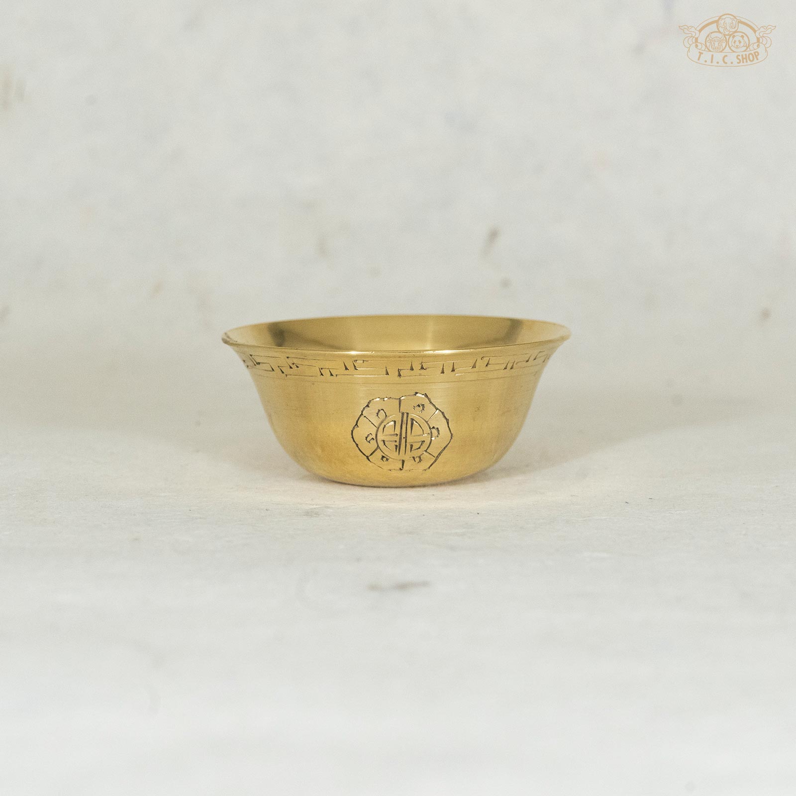 6.5cm Brass offering bowl with ornamental designs, displayed against a textured background.