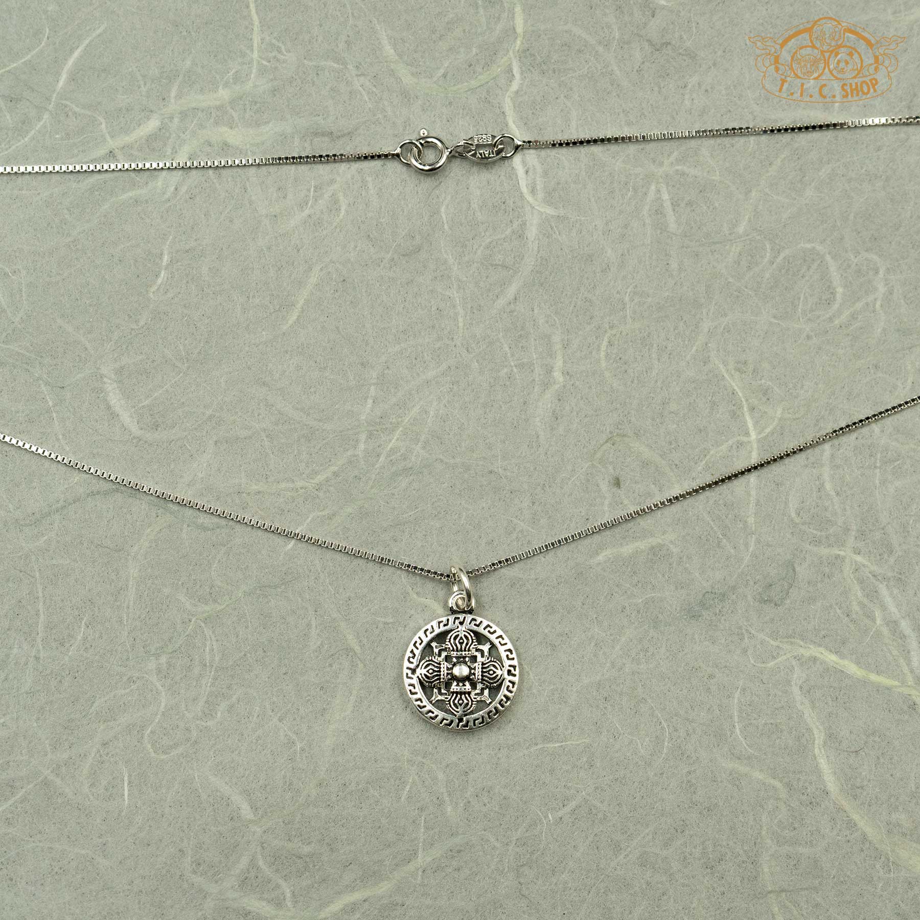 The Double Vajra silver pendant suspended on a 45cm silver chain, displayed against a textured paper background.