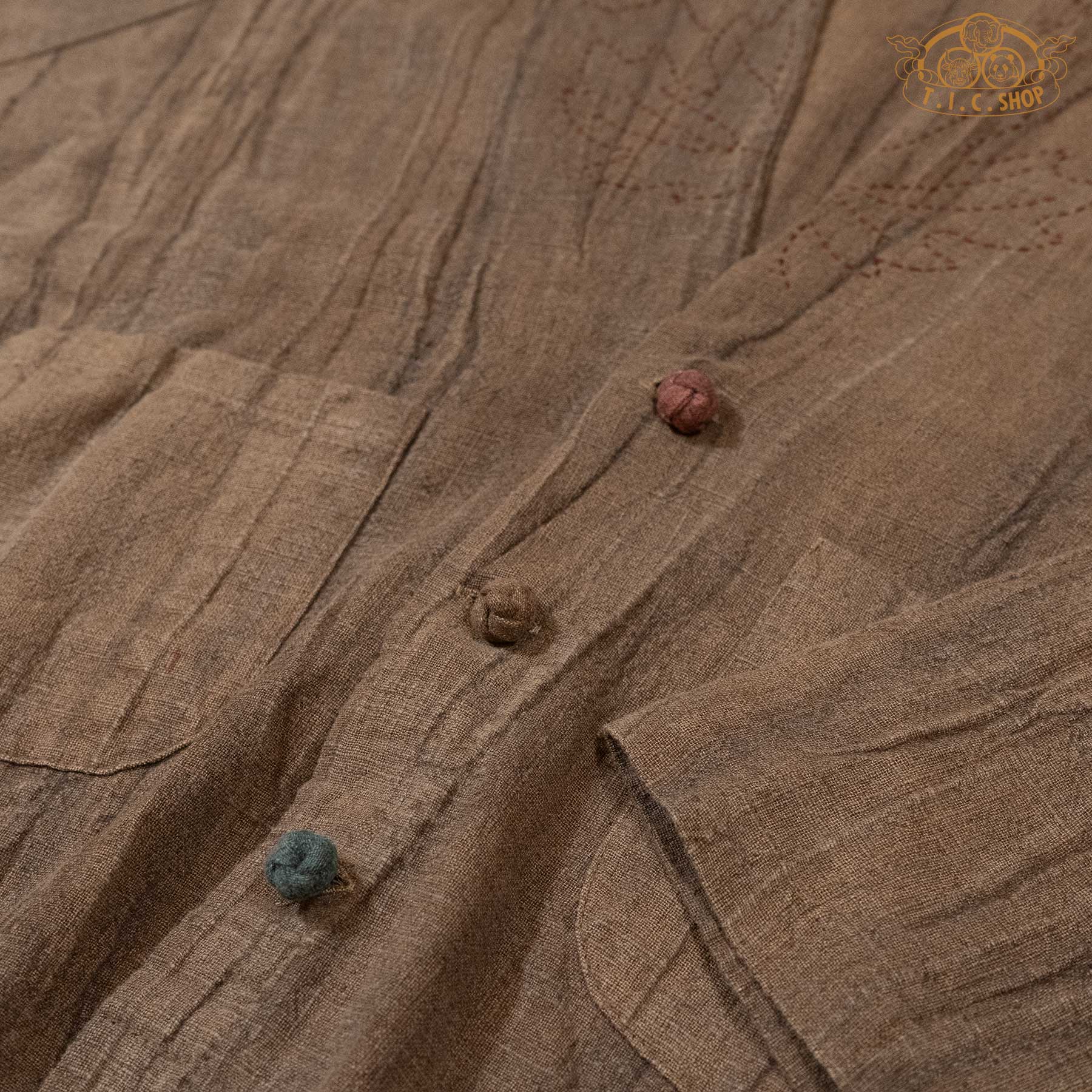 Macro shot of the unique handmade buttons showing the artisanal color scheme and textured linen fabric