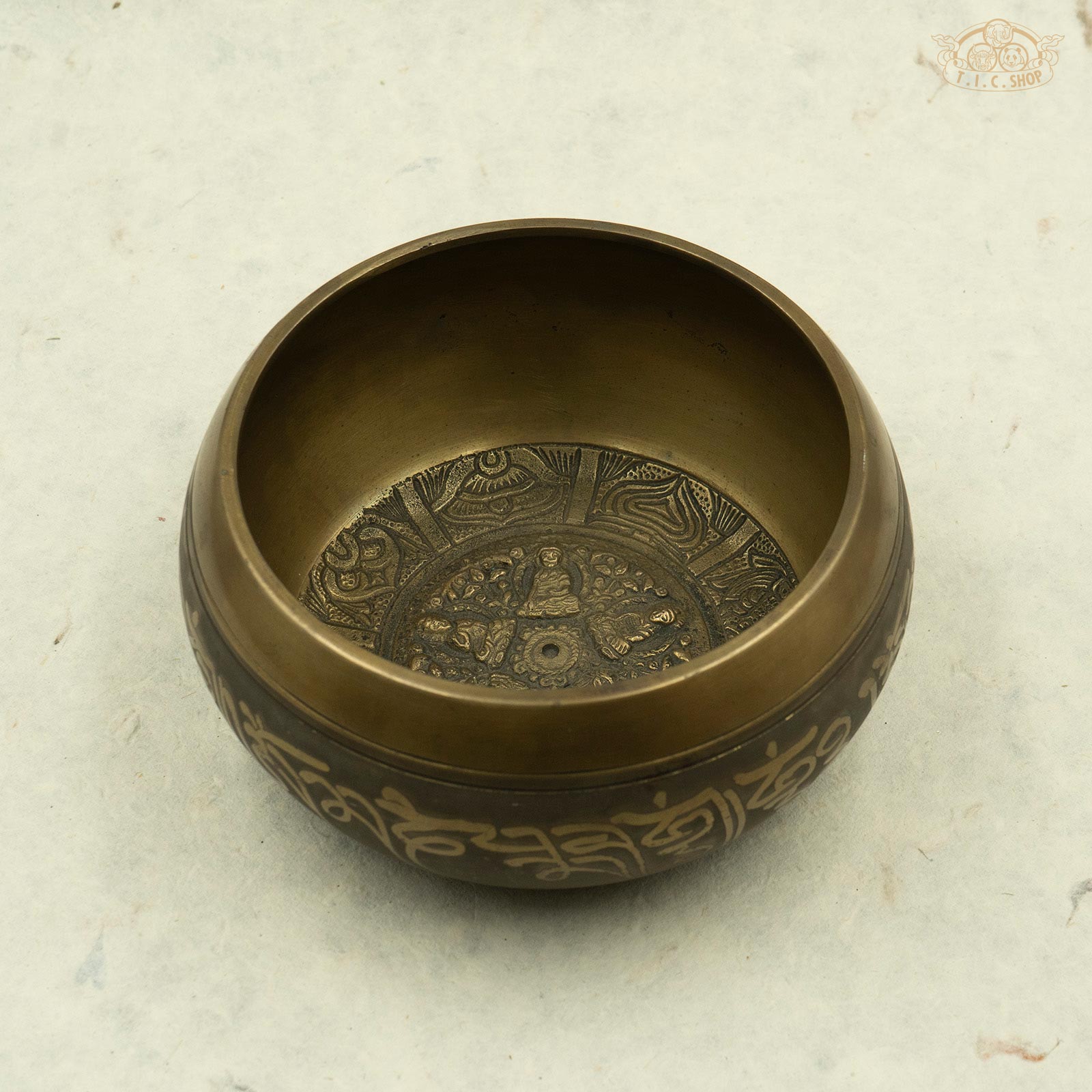 Front view of Tibetan brass singing bowl with an image of five buddhas seated around the rim, handcrafted in Nepal for meditation