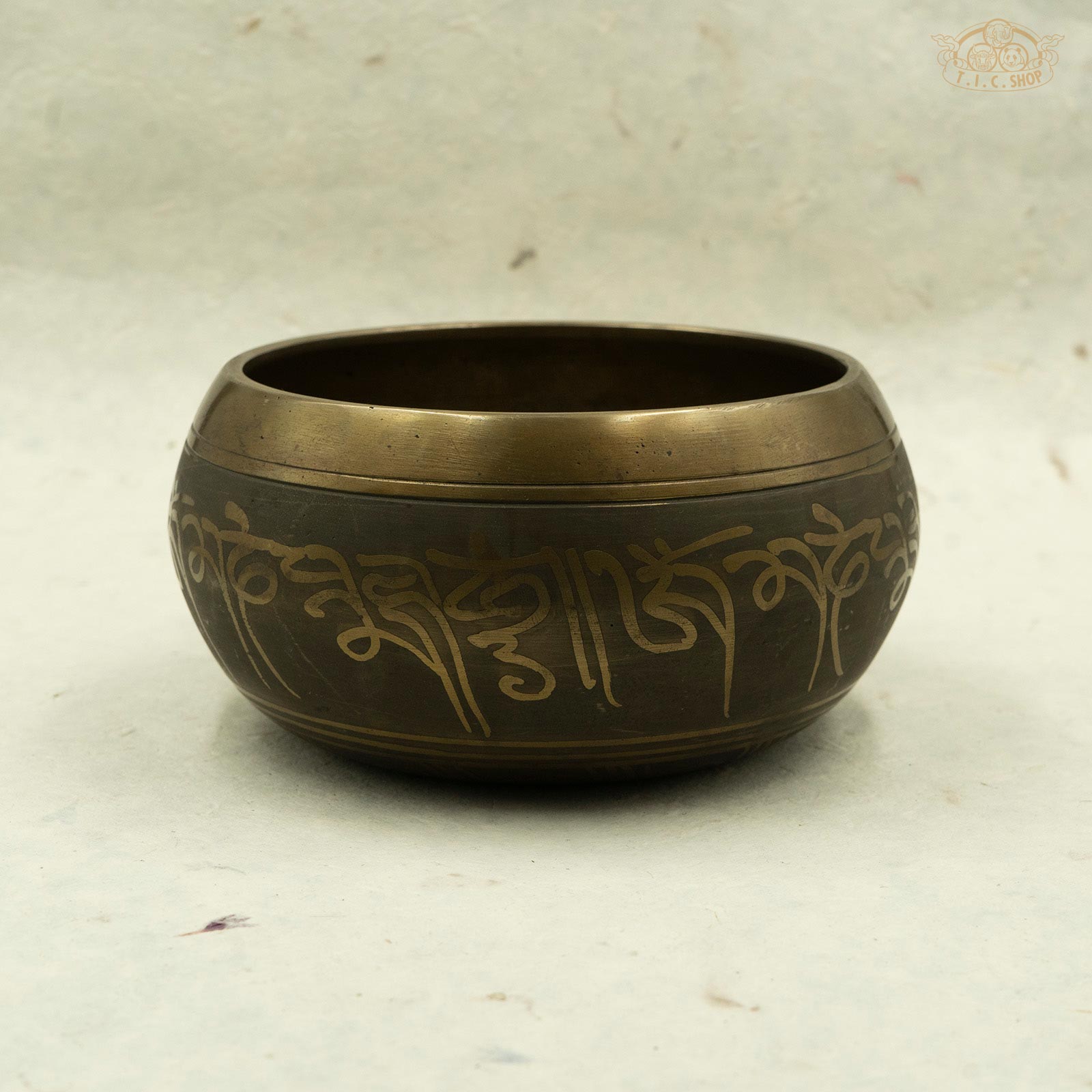 Side view of Tibetan brass singing bowl with intricate symbols and designs, handcrafted in Nepal.