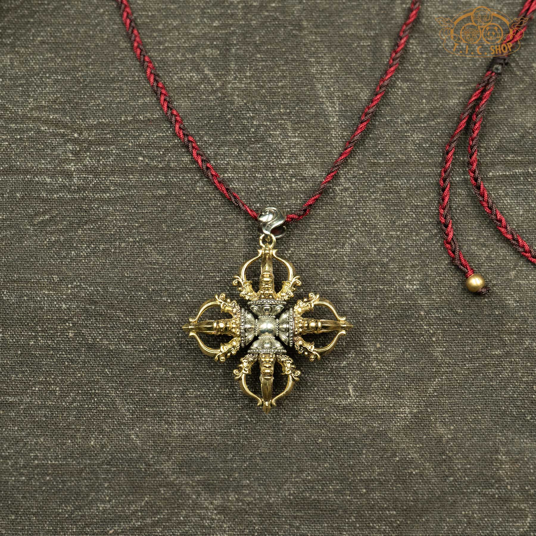 Sculpted brass and cupronickel double vajra pendant showing symmetrical double vajra symbol