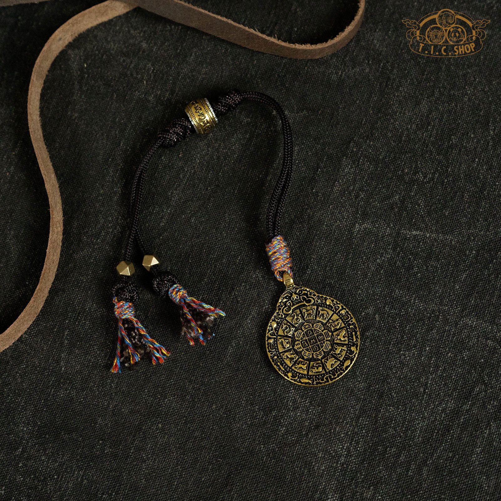 A hand-woven hanging amulet with brass detailing and tassel
