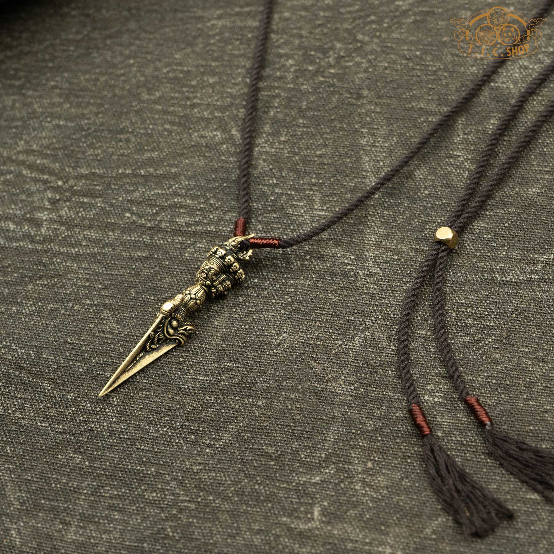 Angled side view of antique brass phurba pendant showing sculpted design and depth