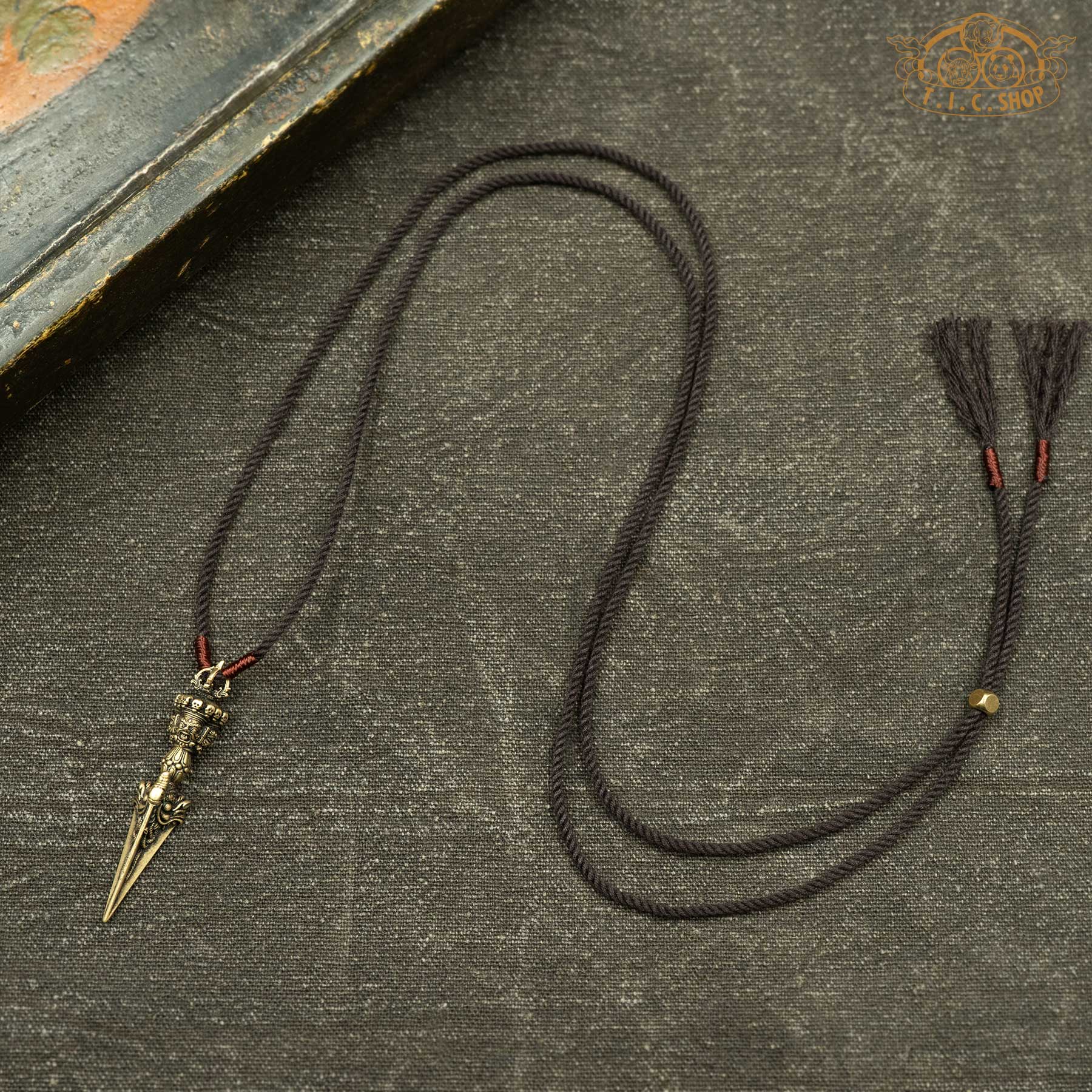 Sculpted phurba pendant displayed with hand-woven brown rope necklace