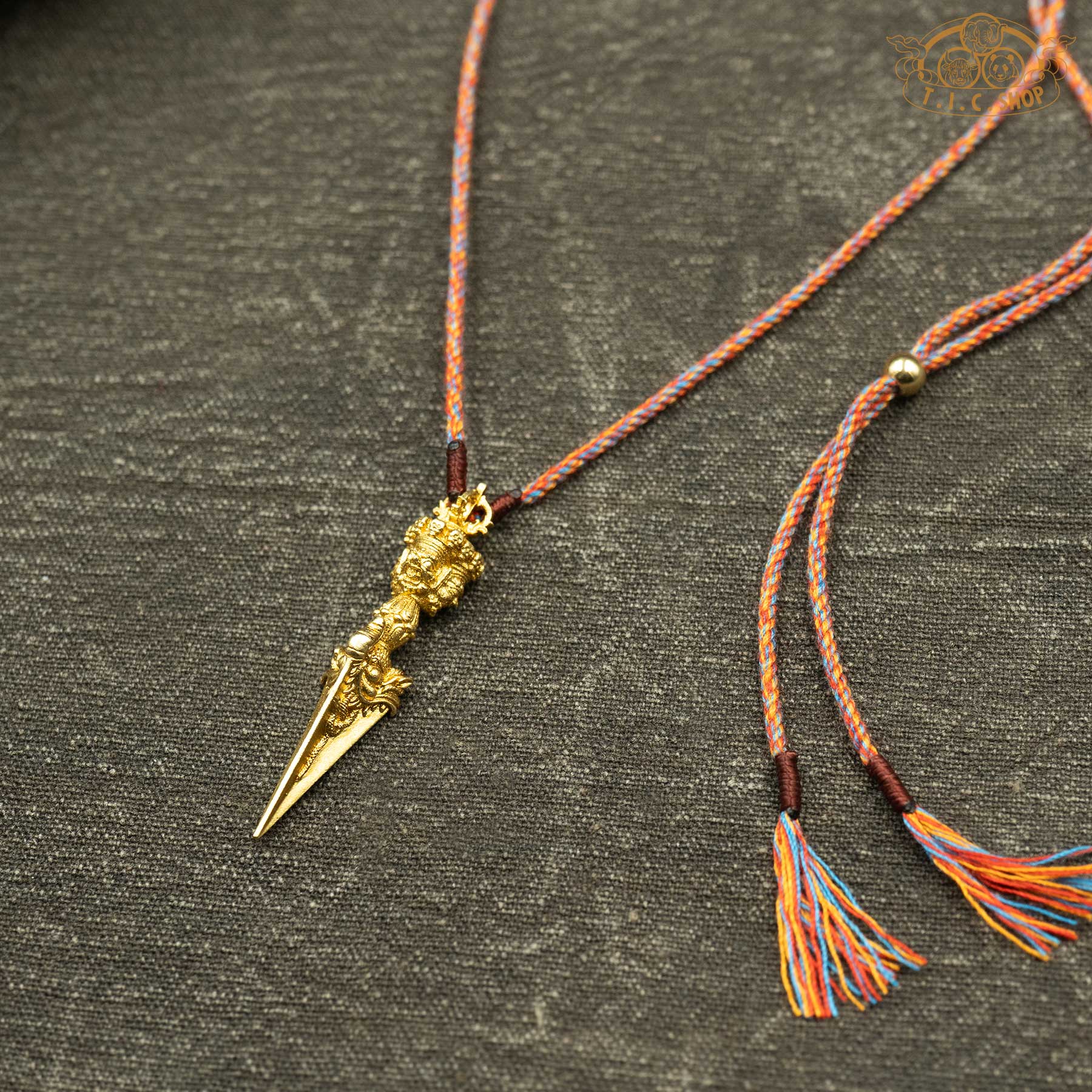 Angled side view of phurba pendant showing sculpted design and depth