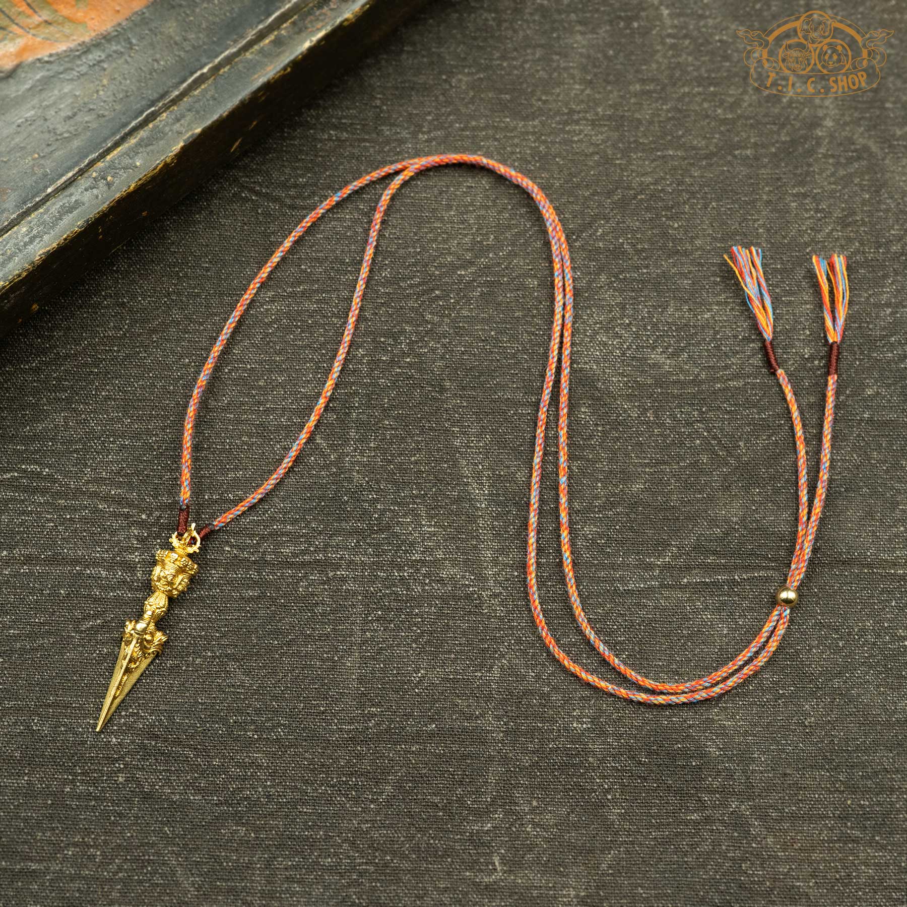 Sculpted phurba pendant displayed with hand-woven orange-toned rope necklace