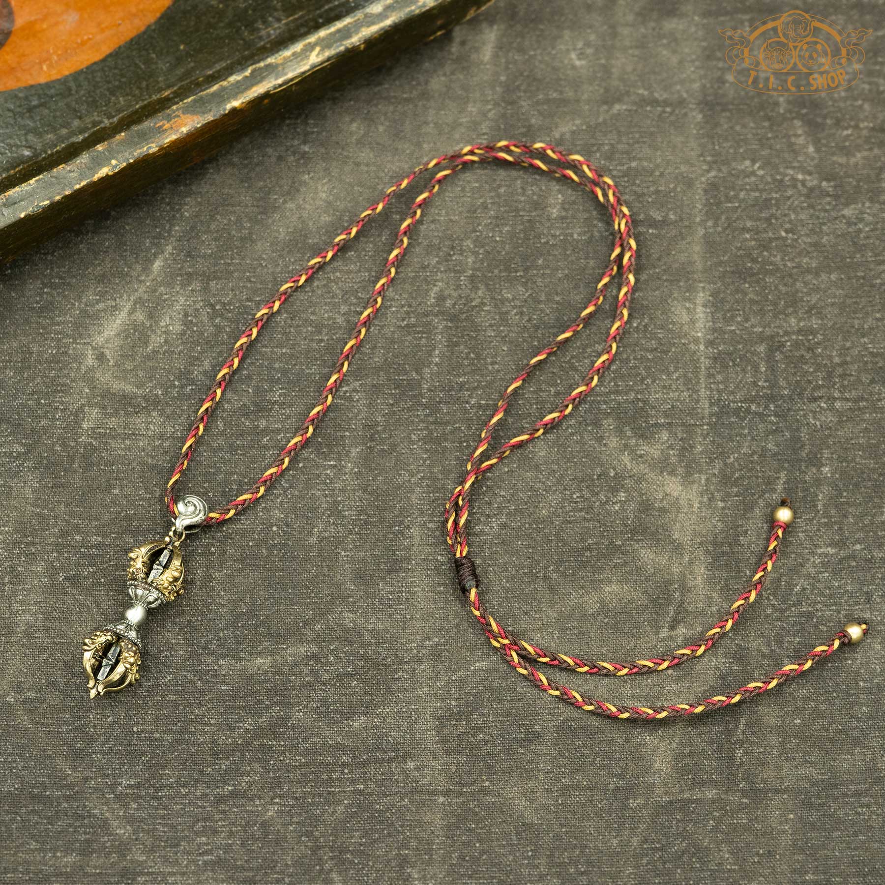 Sculpted vajra pendant displayed with hand-woven red tone rope necklace