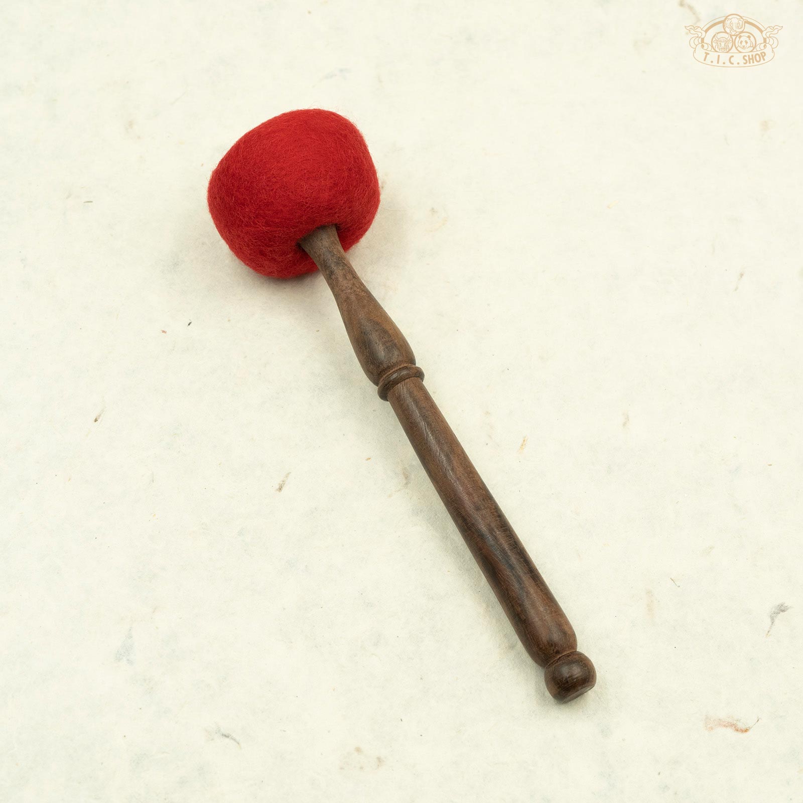 A wooden striker mallet with a red wool tip and a brown wooden shaft, used for playing singing bowls.