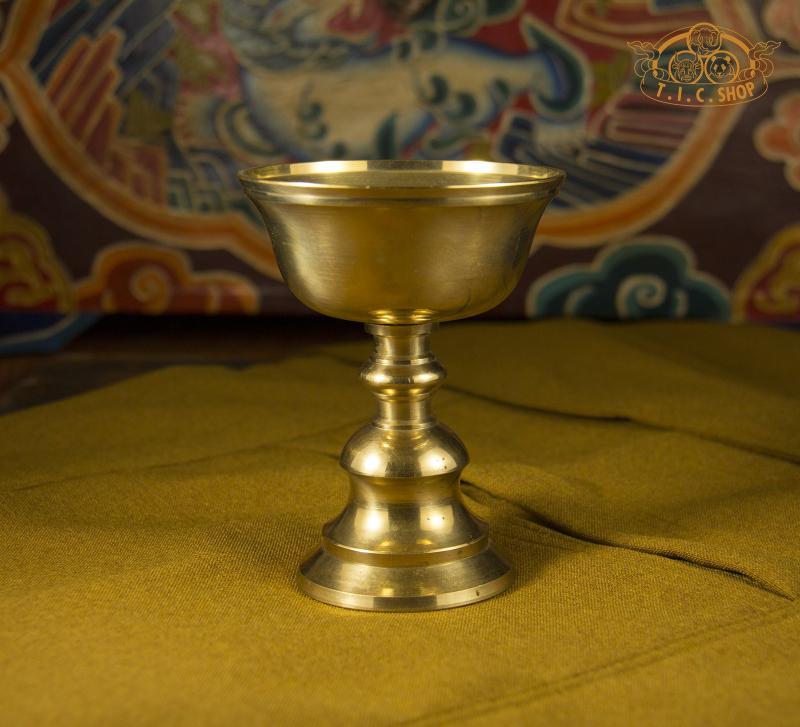 Front view of large brass butter lamp with traditional Tibetan design and polished golden finish.